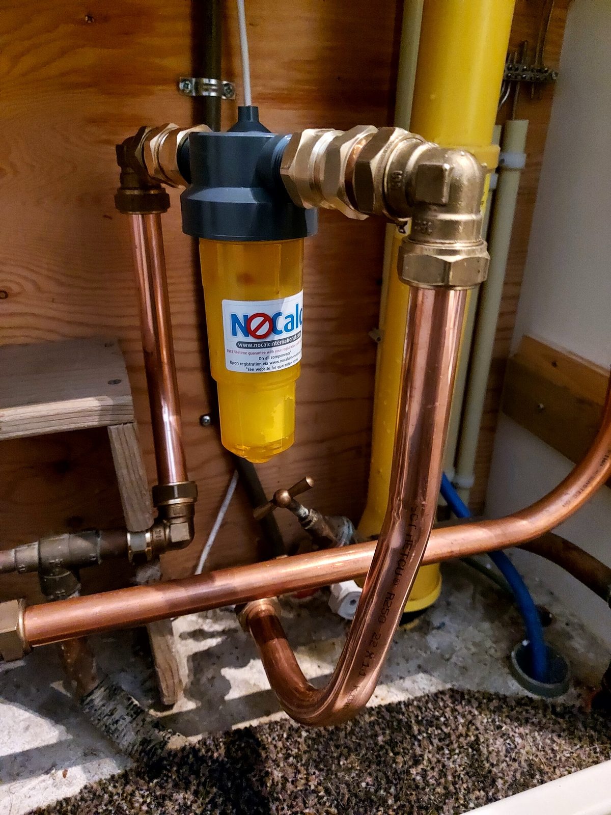 Koperen waterleidingen met een waterfilter naast een gele gasleiding