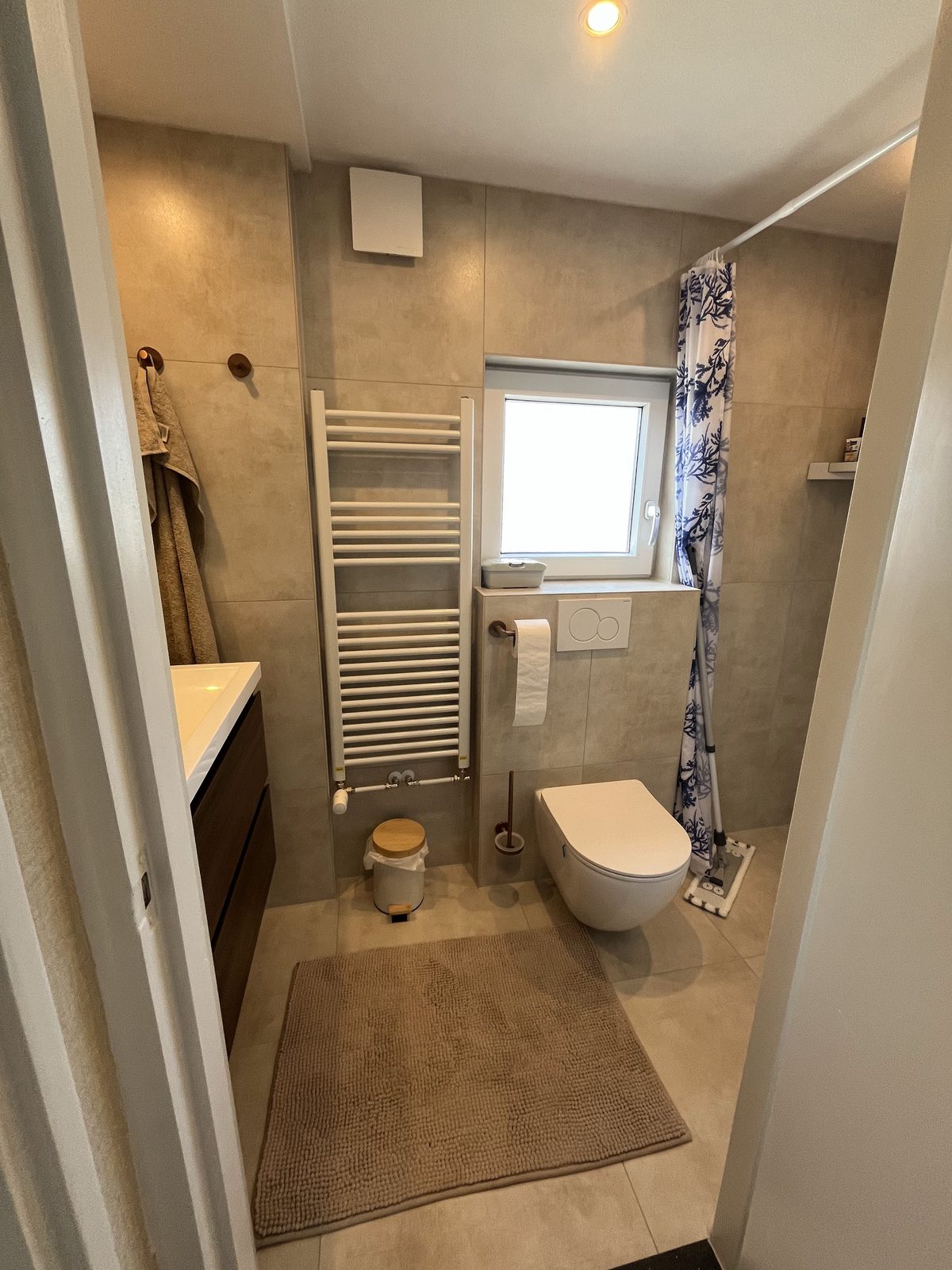 Afgewerkte badkamer met handdoekradiator en zwevend toilet